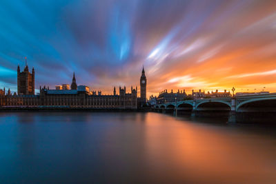 View of bridge over river and buildings against sky at dusk