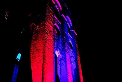 Low angle view of illuminated building against sky at night