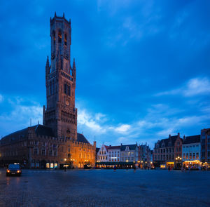 Illuminated buildings in city against sky at dusk