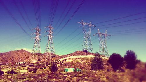 Low angle view of electricity pylon against blue sky