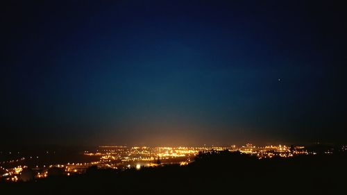 Illuminated cityscape against sky at night