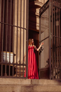 Low angle view of woman in pink evening gown standing at doorway