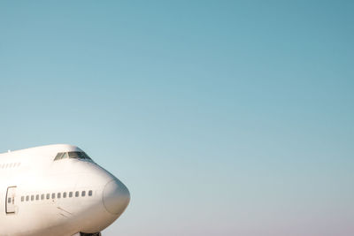 Low angle view of airplane at airport against clear blue sky