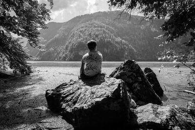 Rear view of boy sitting on rock