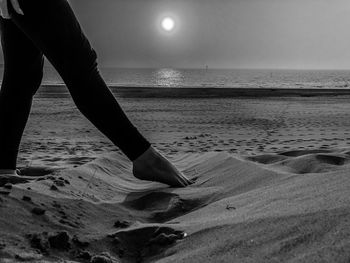 Low section of person on beach against sky