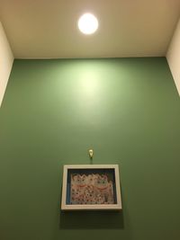 Low angle view of illuminated lamp on wall at home