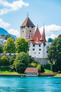 Buildings by river against sky