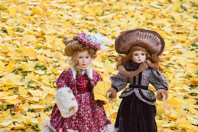 Portrait of a girl standing against yellow autumn leaves