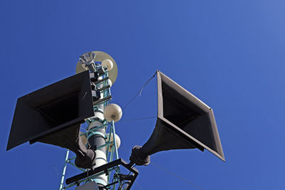 Low angle view of telephone pole against clear blue sky