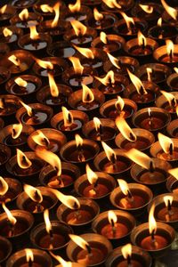 Full frame shot of lit tea light candles at night