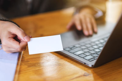 A businesswoman holding and giving a blank business cards while using laptop computer in office