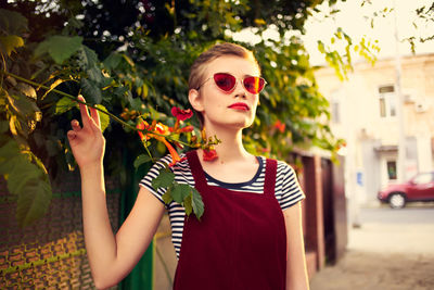 Close-up of young woman standing against plants