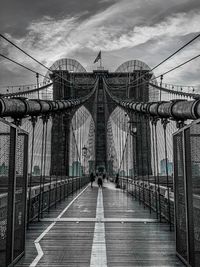 Bridge in city against cloudy sky