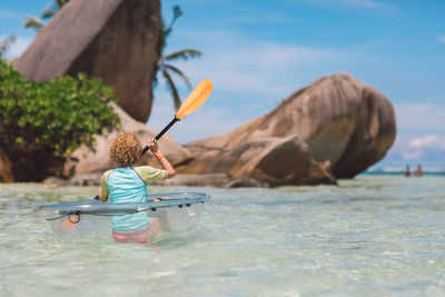 Rear view of woman kayaking in sea