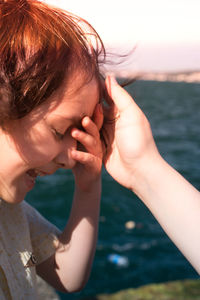 Cute boy crying while standing against sea