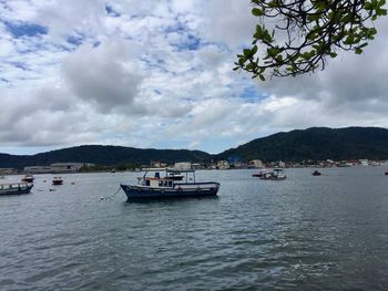 Boat sailing on sea against cloudy sky