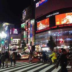 Woman standing on illuminated city street at night