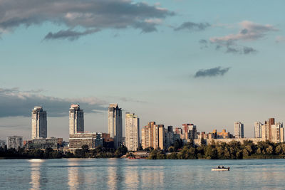 Sea by buildings against sky in city