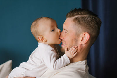 Close-up of a charming 6-month-old caucasian boy biting his dad's nose. the concept of growing teeth