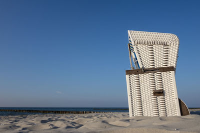 Lifeguard hut on beach against clear blue sky