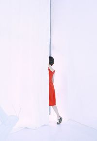 Rear view of woman standing against white wall