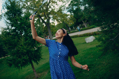 Young woman standing by tree against plants