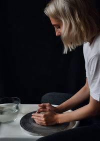 Side view of young woman sitting on table