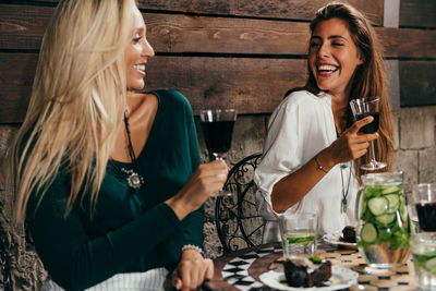 Cheerful female friends having red wine at outdoors restaurant during night