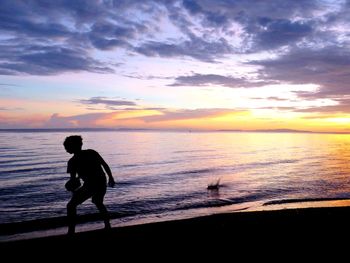 Silhouette of man at beach against sky during sunset