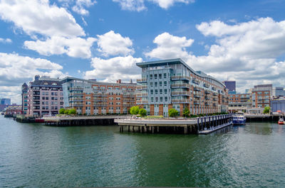 Buildings by river against sky in city