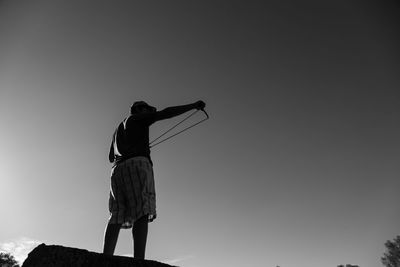 Rear view of silhouette woman standing on field against sky