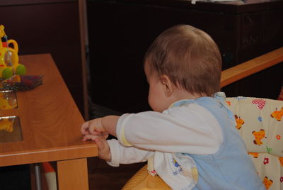 Side view of boy holding baby at home