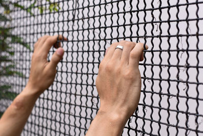 Close-up of hand holding chainlink fence