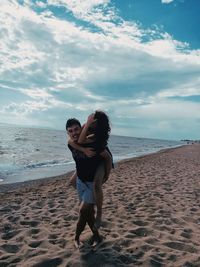 Full length of couple on beach against sky