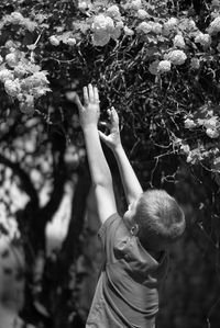 Boy reaching towards flowers in park