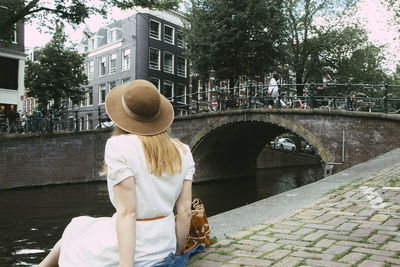 Woman sitting on canal overlooking city