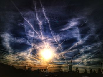 Low angle view of vapor trails in sky at sunset