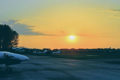 Airplane on runway against sky during sunset