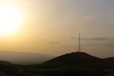 Communications tower on top of silhouette mountain during sunset