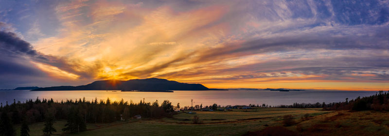 Scenic view of sea against dramatic sky during sunset