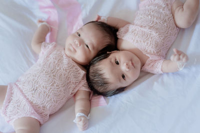 High angle portrait of baby girl lying on bed at home