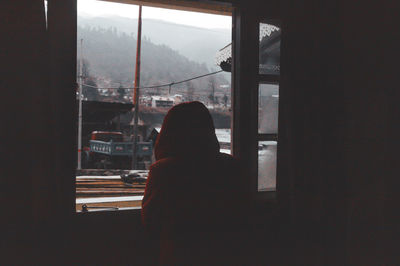 Silhouette woman looking through window