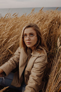 Portrait of beautiful young woman at beach against sky