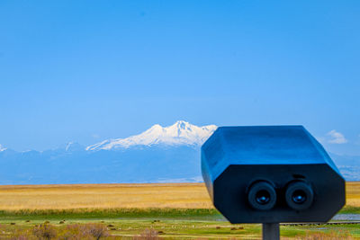 Telephone booth on field against mountain range against blue sky