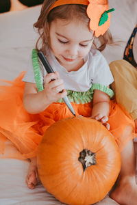 Little toddler girl drawing on a pumpkin making lantern jack on halloween holiday. 
