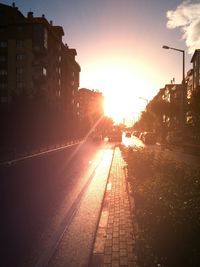 Road amidst buildings against sky during sunset