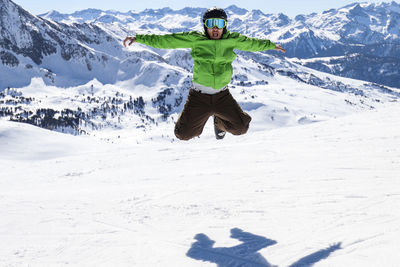 High angle view of person jumping on snowcapped mountain