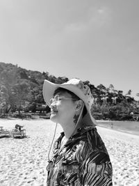 Side view of woman standing at beach against sky