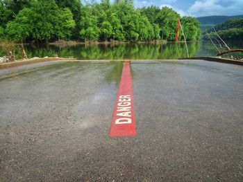 Danger sign on asphalt at boat ramp  against trees