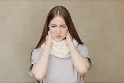 Portrait of young woman standing against wall